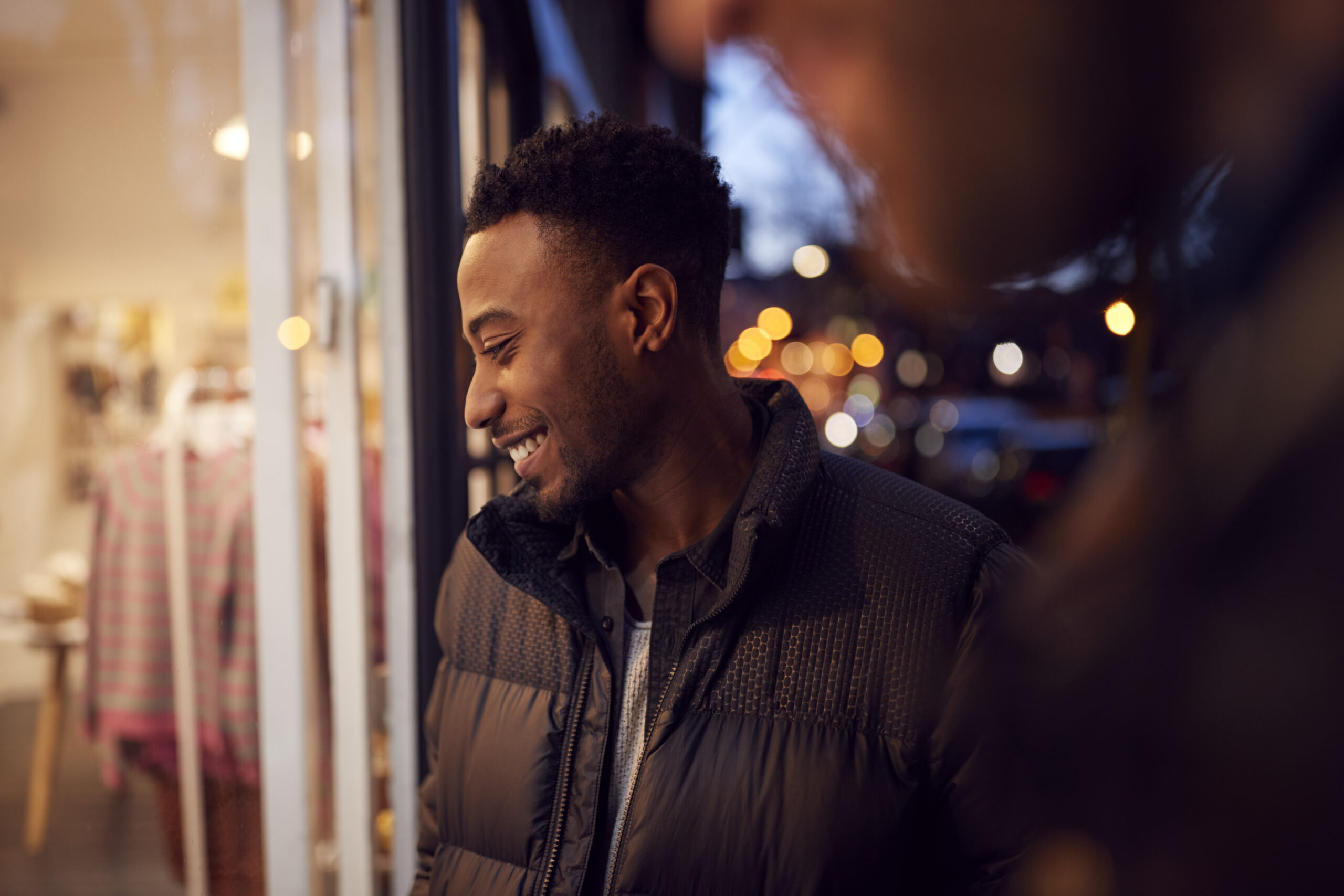 Evening View Of Two Men Window Shopping Looking At Display In Fashion Store